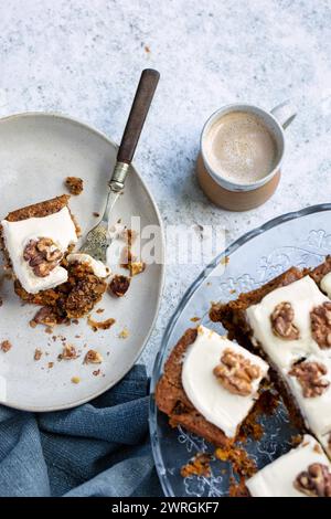 Blick von oben auf einen frisch gebackenen, hausgemachten Karottenkuchen mit Buttercreme, Walnüssen und einer Tasse Kaffee Stockfoto
