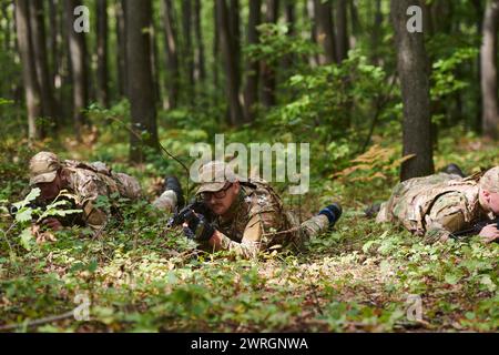 Elite-Soldaten manövrieren heimlich durch den dichten Wald, getarnt in spezieller Ausrüstung, während sie sich auf ein verdecktes und strategisches Militär begeben Stockfoto