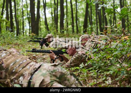 Elite-Soldaten manövrieren heimlich durch den dichten Wald, getarnt in spezieller Ausrüstung, während sie sich auf ein verdecktes und strategisches Militär begeben Stockfoto
