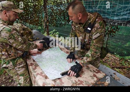 Eine gut ausgebildete Militäreinheit organisiert eine taktische Mission, während sie während einer Besprechung eine Militärkarte studiert Stockfoto