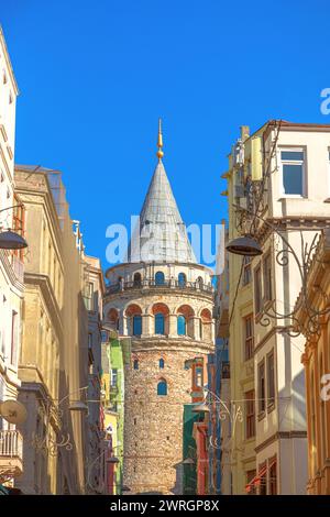 Der alte Galata-Turm steht hoch im Viertel Istanbul Galata, eingerahmt von alten Gebäuden vor einem klaren blauen Himmel der Türkei. Stockfoto