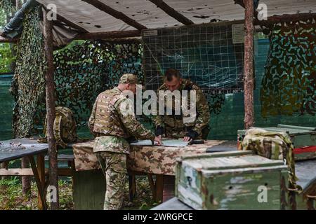 Eine gut ausgebildete Militäreinheit organisiert eine taktische Mission, während sie während einer Besprechung eine Militärkarte studiert Stockfoto