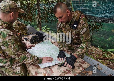 Eine gut ausgebildete Militäreinheit organisiert eine taktische Mission, während sie während einer Besprechung eine Militärkarte studiert Stockfoto