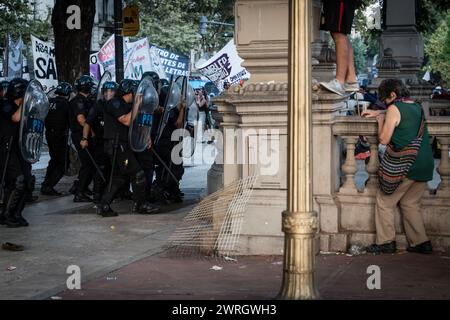 Buenos Aires, Argentinien. Februar 2024. Eine ältere Frau schützt sich vor dem aggressiven Vormarsch der Polizei während der Demonstration. Das Omnibus-Gesetz mit mehr als 600 Artikeln, die von Präsident Javier Milei vorgestellt wurden, brachte Dutzende von Stunden parlamentarischer Debatte mit sich, begleitet von mehreren Tagen des Widerstands der Bevölkerung auf den Straßen rund um den Nationalkongress. Diese Tage waren geprägt vom politischen Faden, den Verhandlungen, dem hin und her, dem Protest und der Unterdrückung. Das Jahr 2024 in Buenos Aires, Argentinien, begann mit Tränengas, Stöcken, Gummikugeln und Gesetzen, die sich erheben und fallen Stockfoto