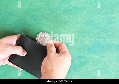 Menschliche Hand, die schwarze Brieftasche mit Bitcoin-Münze hält. Kryptowährung für Zahlungskonzept. Stockfoto