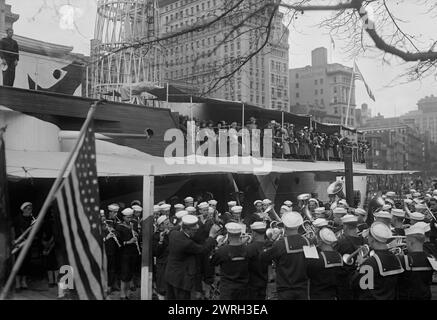 Französische Frauen auf REKRUTEN, 1917 oder 1918. Eine Militärkapelle, die neben der USS Recruit spielt, einem hölzernen Modell eines Schlachtschiffs, das von der Navy am Union Square in New York City gebaut wurde, um Seeleute zu rekrutieren und Liberty Bonds während des Ersten Weltkriegs zu verkaufen Französische Frauen stehen an Deck. Stockfoto