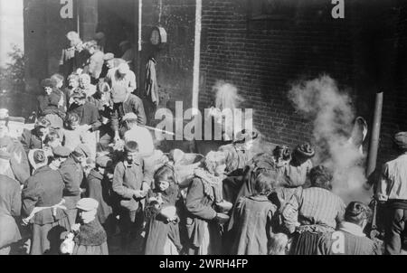 Arm in Nordfrankreich ernährte sich zwischen 1914 und 1915 von der deutschen Feldküche. Vor einem Backsteingebäude in Nordfrankreich während des Ersten Weltkriegs waren hauptsächlich Frauen und Kinder Stockfoto