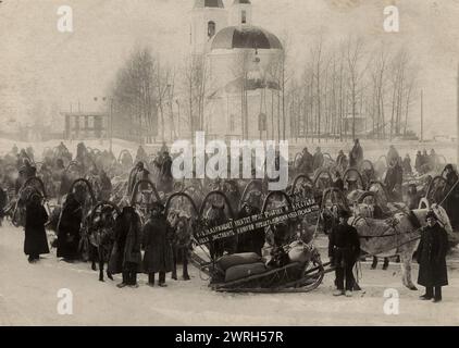 Roter Konvoi mit Brot vor dem Hintergrund der Sretenskaja-Kirche, 1920-1929. Aus einer Sammlung von 153 Fotografien und Dokumenten, die aus den persönlichen Archiven von Menschen stammen, die im späten 19. Und frühen 20. Jahrhundert in der Stadt Berdsk lebten. Die Kollektion bietet Einblicke in den Alltag, die Atmosphäre und die Aktivitäten in Berdsk, einem der wichtigsten Zentren der Getreideverarbeitung zu dieser Zeit. Die Fotos zeigen Gruppen von Schülern und Lehrern, einheimische Mühlen, Menschen in Landwirtschaft und Industrie, Soldaten, Kinder und Jugendliche. Die meisten stammen aus der frühen sowjetischen Ära. Das Dokument Stockfoto