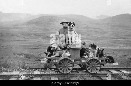Mann und Hunde auf dem Zug von Shelton nach Nome, 1912. Walter W. Johnson, ein Bergbauingenieur und Designer von Gold- und Zinnbaggern, der mit seiner Familie „Pupmobil“ und zu Pferd über die Halbinsel Seward reiste. Stockfoto
