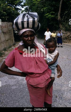 18. Mai 1994; Port-au-Prince, Haiti-Eine Straßenszene in der Innenstadt von Port-au-Prince. Man sieht Frauen, die schwere Lasten auf dem Kopf tragen und gerade nur ri ausbalancieren Stockfoto