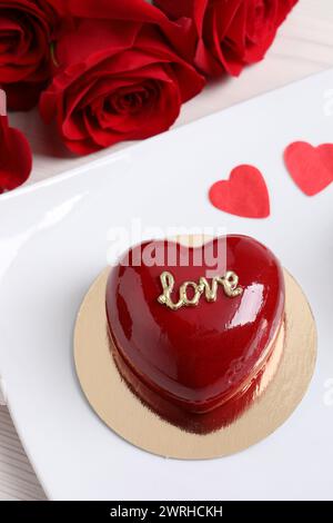 St. Valentinstag. Köstlicher herzförmiger Kuchen und Rosen auf dem Tisch Stockfoto