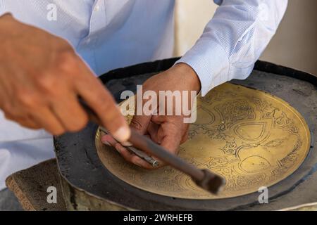 27. JUNI 2023, BUCHARA, USBEKISTAN: Der Meister, der die Metallarbeiten für den Verkauf als Souvenir macht Stockfoto