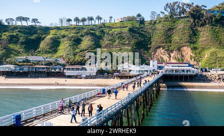 Malibu Pier, Hochwinkelansicht. Pier in Malibu, Kalifornien, an einem sonnigen Sommertag mit Touristen, die auf der Promenade entlang der Küste spazieren gehen. Stockfoto