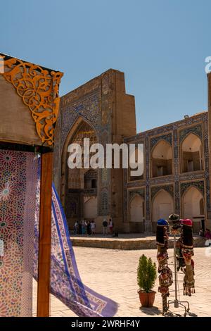 27. JUNI 2023, BUCHARA, USBEKISTAN: Schöne ethnische Stoffe, die mit dem Wind wehen, neben der alten Madrasah, Buchara, Usbekistan. Selektiver Fokus mit Stockfoto