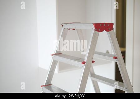 Metal ladder standing in empty room, renovation and improvement concept. Stockfoto