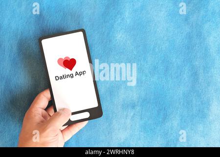 Hand mit Mobiltelefon mit Online-Dating-App. Suche nach Liebespartner online. Stockfoto