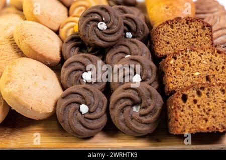 Aus nächster Nähe sehen Sie eine köstliche Auswahl an Backwaren, darunter Brot, Gebäck und Kekse, die alle auf einem charmanten rustikalen Holzbrett ausgestellt sind Stockfoto