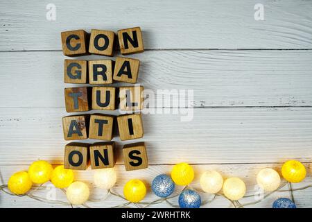 Herzlichen Glückwunsch Buchstaben mit LED-Baumwollkugeln Dekoration auf hölzernem Hintergrund Stockfoto