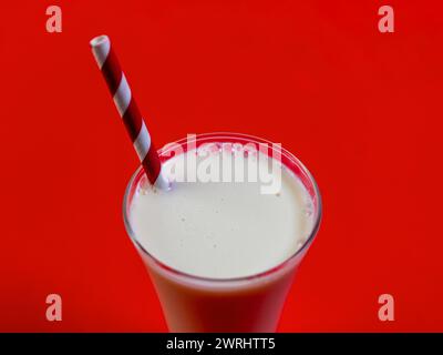 Ein dicker und cremiger Milchshake in einem hohen Glas, gekrönt mit einem rot-weiß gestreiften Strohhalm Stockfoto