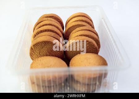 Eine Nahaufnahme einer Vielzahl von Cookies in einem durchsichtigen Kunststoffbehälter, isoliert auf weißem Hintergrund. Stockfoto