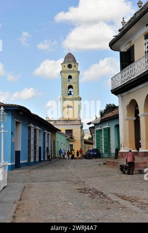 Blick auf eine Kopfsteinpflasterstraße zum Kirchturm unter klarem Himmel, Trinidad, Kuba, Zentralamerika Stockfoto