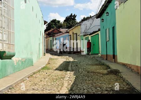 Straßenszene in Kuba mit farbenfrohen Häusern und Kopfsteinpflasterpfaden bei Tageslicht, Trinidad, Kuba, Zentralamerika Stockfoto