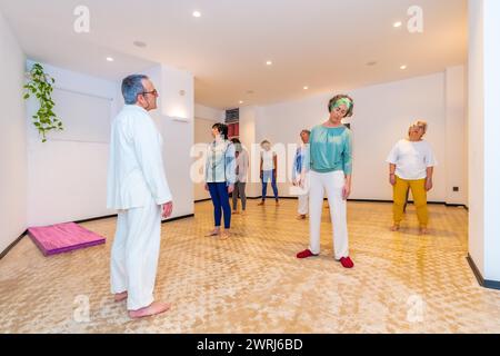 Gruppe reifer kaukasischer Frauen, die sich während des Qigong-Kurses ausdehnen, geführt von einem Lehrer Stockfoto