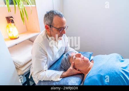 Reifer Therapeut bei einer reiferen Frau in einer Klinik eine orientalische Nackenmassage Stockfoto