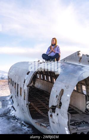 Frau, die auf dem Flugzeug von Solheimasandur sitzt, konzentrierte sich auf Meditation in Island Stockfoto