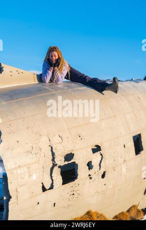 Frau, die glücklich im Flugzeug in Solheimasandur sitzt und in ihrem Urlaub in Island lächelt Stockfoto