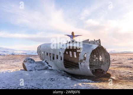 Frau, die auf dem Flugzeug von Solheimasandur sitzt, mit offenen Armen in der Meditation in Island Stockfoto