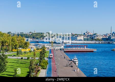 Fußgänger genießen einen sonnigen Tag an einer Uferpromenade mit Blick auf den Yachthafen in Istanbul, in Istanbul, Turkiye Stockfoto