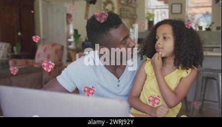 Bild von Blumenherzen über glücklichen afroamerikanischen Vater und Tochter, die High Five machen Stockfoto
