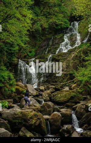 Weibliche Touristin am Torc Waterfall im Killarney National Park, County Kerry, Irland Stockfoto