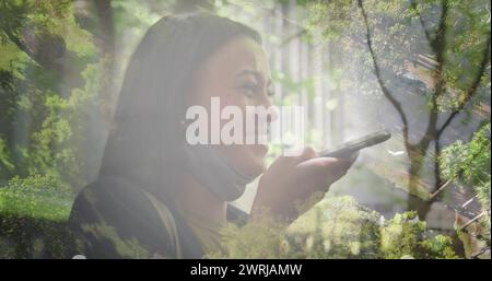 Bild einer glücklichen birassischen Frau mit Smartphone über Landschaft Stockfoto