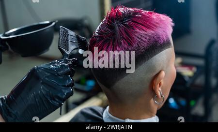 Der Friseur färbt das Haar einer Asiatin in Rosa. Kurzer, extremer Haarschnitt. Stockfoto
