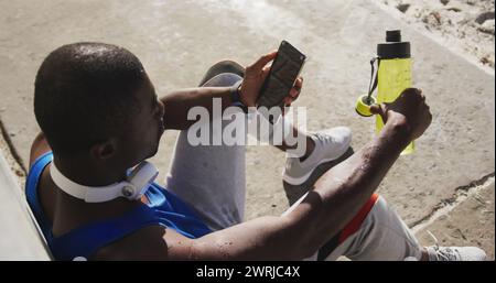 Bild: Benachrichtigungssymbole über das Üben eines afroamerikanischen Mannes, der mit dem Smartphone eine Pause einlegt Stockfoto