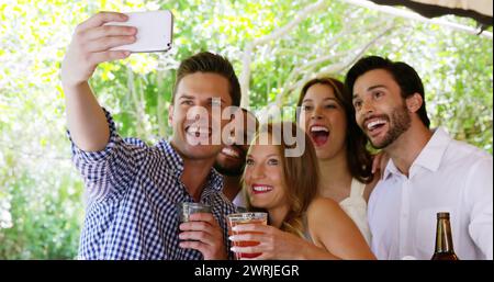 Emoji-Ikonen fliegen, während verschiedene Freunde ein Selfie auf einer Party in 4K machen. Stockfoto