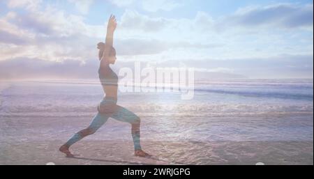 Seitenansicht einer Frau, die an einem sonnigen Tag Yoga am Strand macht Stockfoto