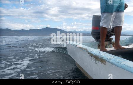 Ein Mann, der ein kleines motorisiertes Fischerboot in Mexiko mit Textfeld steuert Stockfoto