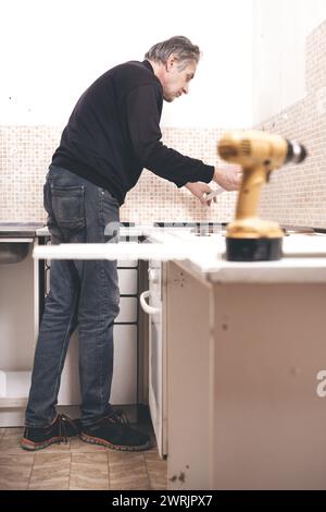 Ein älterer Mann zerlegt die Wohnküche außer Betrieb Stockfoto