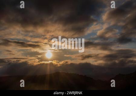 Ein Sonnenuntergang mit Sonnenstrahlen zwischen den Wolken, mystische Szene mit Platz für Text Stockfoto