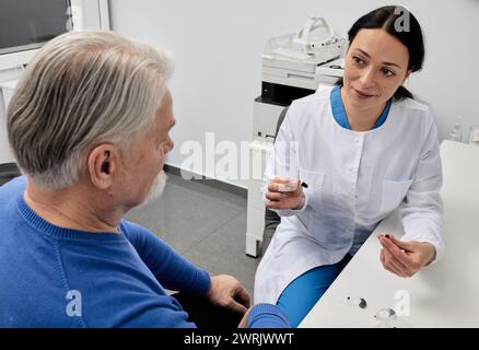 Audiologin Sprechstunde bei grauhaarigem Seniorenpatienten mit Hörproblemen im Hörzentrum. Hörarztkonsultation Stockfoto