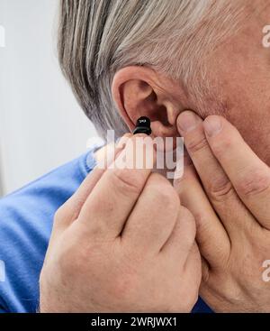 Hörgerät im Ohr des älteren Mannes, Nahaufnahme. ITC-Hörgerät zur Hörbehandlung Stockfoto