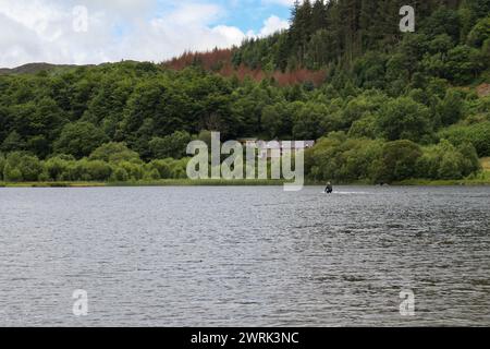 Ein ruhiger See mit ländlichen Strukturen am Ufer, umgeben von üppigem Grün Stockfoto