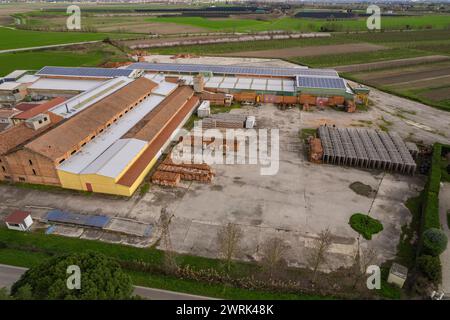 Die Luftaufnahme zeigt ein Industriegebäude in der flachen Ebene von Pianura Padana, in dem verschiedene Geräte und Maschinen in Betrieb sind. Die sce Stockfoto