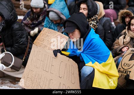 Junge ukrainische Patrioten knieten während der Schweigeminute zu Ehren der gefallenen Verteidiger der Ukraine bei einer öffentlichen Demonstration. Kiew - 10. Februar 2024 Stockfoto