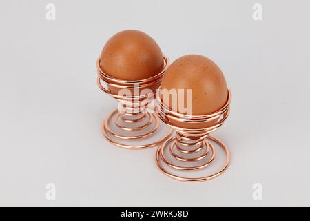 Zwei große Freilandeier in roségoldenen oder kupfernen Spiraleiern vor hellem Hintergrund bearbeitbar Stockfoto