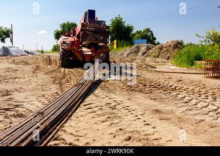 Gabelstaplermaschinen für Transport und Transport heben ausgewählte lange, rostige Ankerstangen auf der Baustelle vom Boden. Stockfoto
