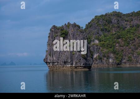 Aus den smaragdgrünen Gewässern der Halong-Bucht, Vietnam, entspringt eine Kalksteinkarstinsel. Die Insel ist ein dramatischer Anblick, mit ihren steilen Klippen, die Hunderte von Stockfoto